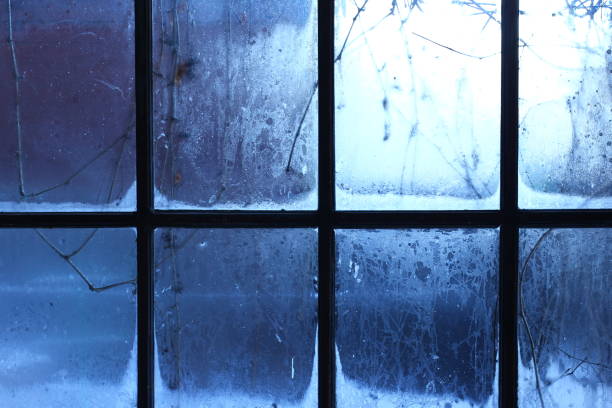 Finestra invernale, gocce d'acqua e fiocchi di neve su un vetro della finestra. - foto stock