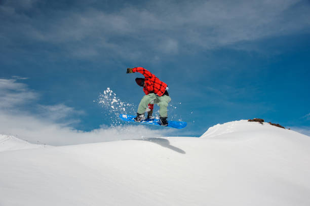 istock guy is jumping on a blue snowboard from a snowy mountain 1042897478