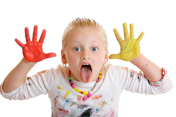 Beautiful young female child full of paint makes grimace stock photo