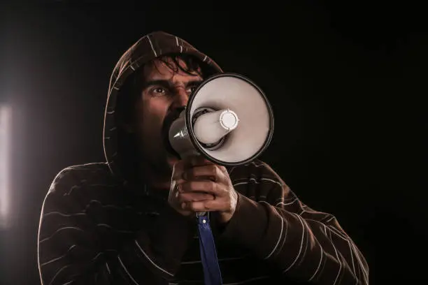 Angry man shouting on megaphone. About 25 years old, Caucasian male.