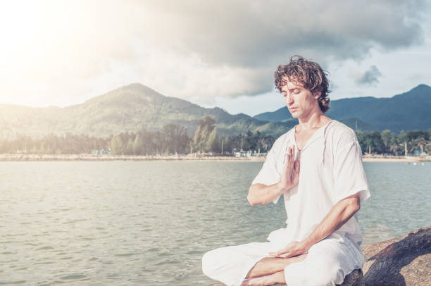 istock Young man doing pranayama practice on the beach 1042914626