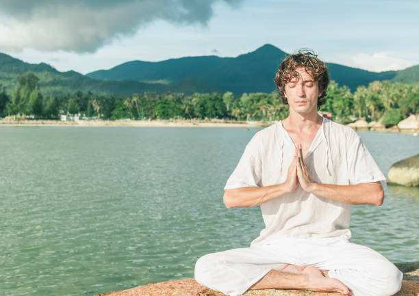 istock A young man meditates on a rocky seashore with Namaste hands 1042914640