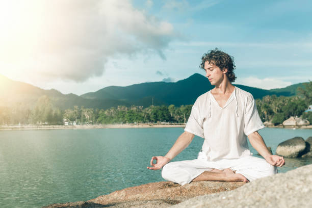 istock A young man meditates on a rocky beach 1042914700