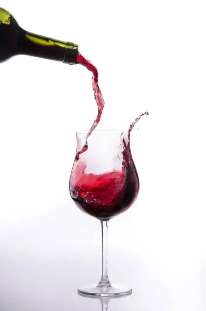 Red wine poured into a glass goblet generates a splash