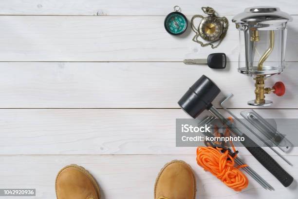 Travel Item Frame For Holiday Relax And Adventure With Knife Boots Lantern Car Key Compass Clock Rubber Hammer Anchor And Tent Rope On White Vintage Wood Floor Or Table Top View For Background Stock Photo - Download Image Now