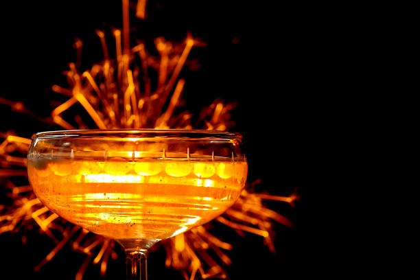 champagne glasses close-up with lit sparkler on black background