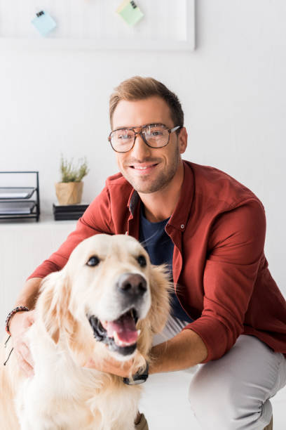 istock man in glasses hugging golden retriever and looking at camera 1042942690
