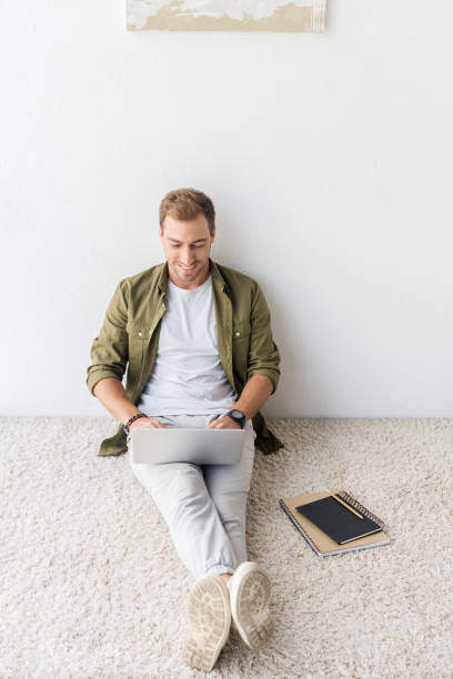 istock casual freelancer using laptop on beige rug 1042948768