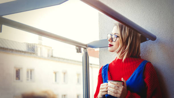 istock Girl with cup sitting at balcony 1042964606
