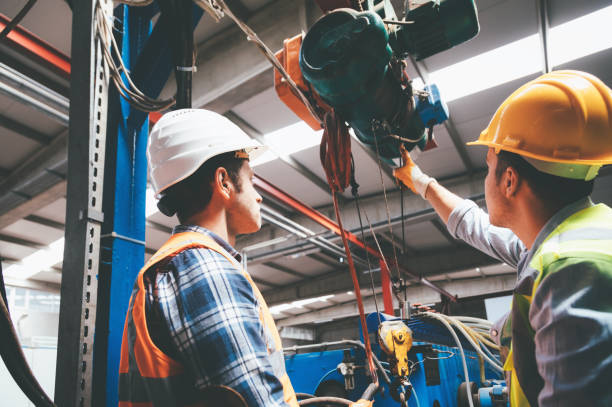 employés de sexe masculin de machines industrielles travaillant avec télécommande pour faire fonctionner la grue - crochet équipement photos et images de collection