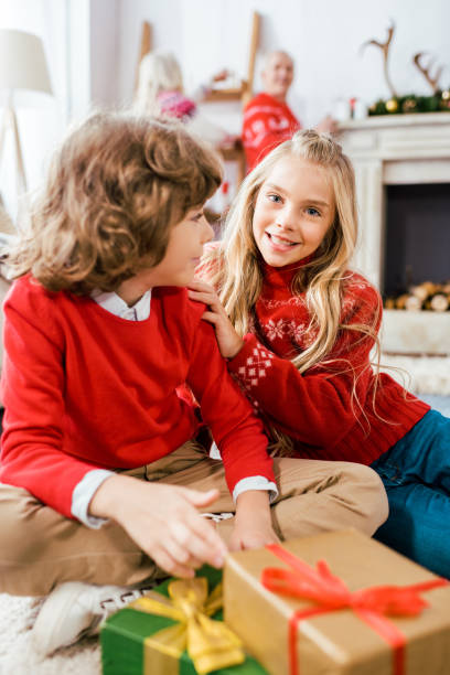 istock adorable siblings in red sweaters sitting on floor with christmas boxes 1042968248