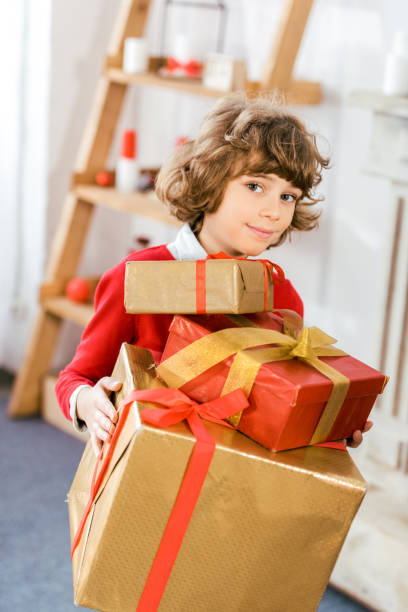 istock adorable happy kid holding stack of christmas gift boxes 1042968280