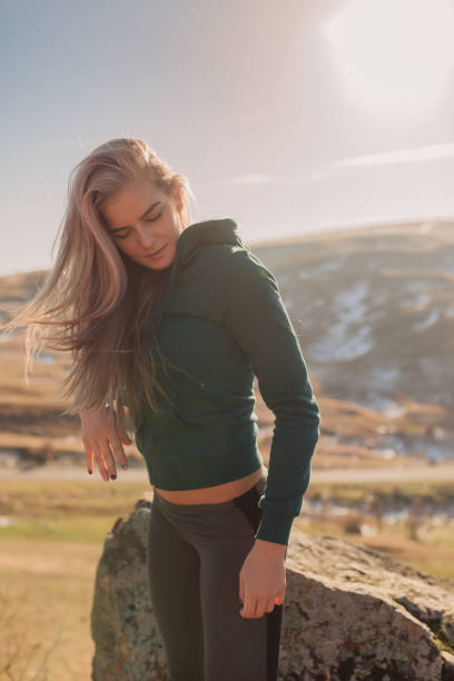 Young fit woman exercising and stretching on a mountain top on a sunny day