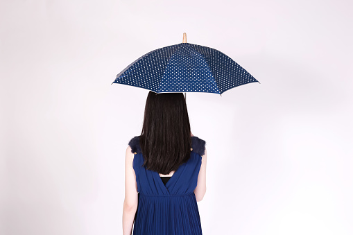 Rear view of business woman back holding an opening umbrella in white isolated background