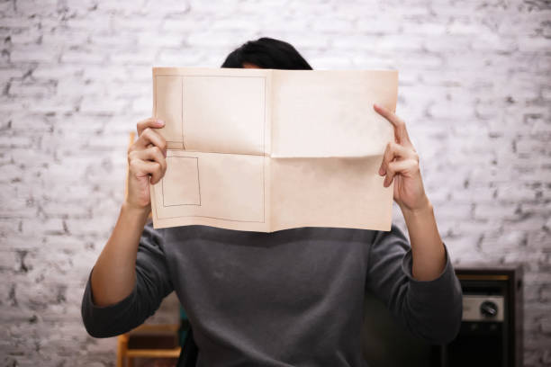 istock Young businessman holding an empty mockup newspaper - ready to insert any text onto publication paper. 1042976688