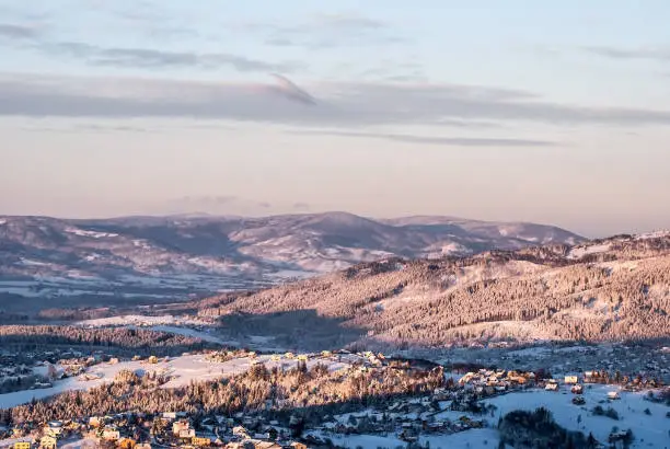 frozen winter scenery with Koniakow village,frozen  hills around and blue sky with few clouds from Ochodzita hill in Beskid Slaski mountains in Poland