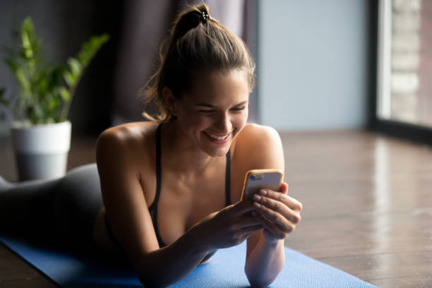 jeune femme sportive tenant smartphone, à l’aide de app - bikram yoga pilates beautiful photos et images de collection