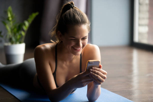 アプリを使って、スマート フォンを保持している若いスポーティな女性 - bikram yoga pilates beautiful ストックフォトと画像