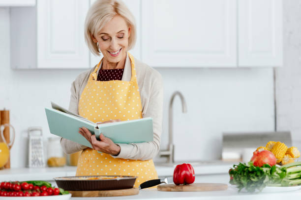 istock smiling senior woman reading recipe book while cooking at kitchen 1042990094