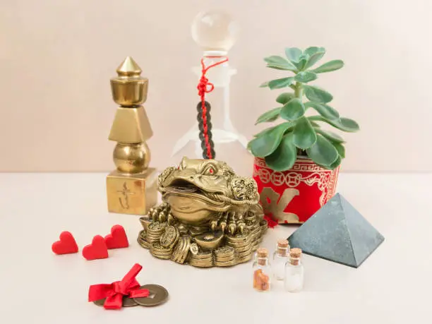 Feng Shui art of harmony of space. Various baubles symbolizing feng shui: Wind music, Chinese coins, pyramid, pagoda, frog, lilac napkin, aroma, salty water. Cozy house. Succulent.