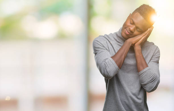 istock Young african american man over isolated background sleeping tired dreaming and posing with hands together while smiling with closed eyes. 1043000080