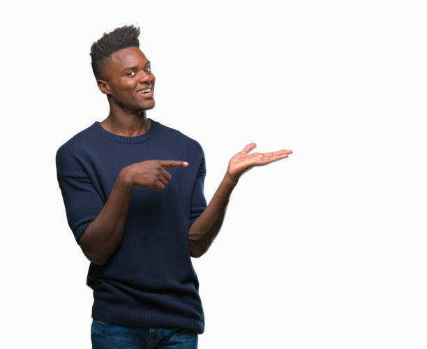 istock Young african american man over isolated background amazed and smiling to the camera while presenting with hand and pointing with finger. 1043002790