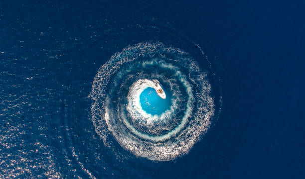 a boat is driving in a circle and produces a big whirlpool - nautical vessel fotos imagens e fotografias de stock