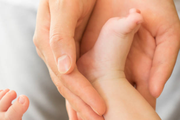 istock Mother's hands carefully keeping baby's foot with tenderness 1043008664