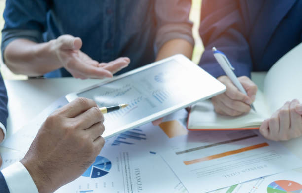istock Businessteam are analyzing graphs.They use a tablet and have secretary take notes. 1043031590