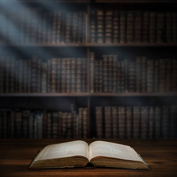 istock Open old book on a bookshelf background and the rays of light. 1043035338