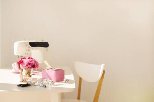 Workplace for sewing and needlework in a bright room with white furniture. Blurring effect and selective focus.