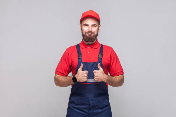 praca jest skończona! portret młodego zadowolonego wesołego mechanika z brodą w kolorze niebieskim, czerwoną koszulką i czapką, stojącą i ukazującą thumps z uśmiechem. - t shirt men red portrait zdjęcia i obrazy z banku zdjęć