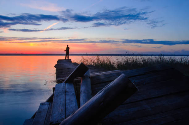 istock Fisher on evening old pier on the lake at sunset 1043045942