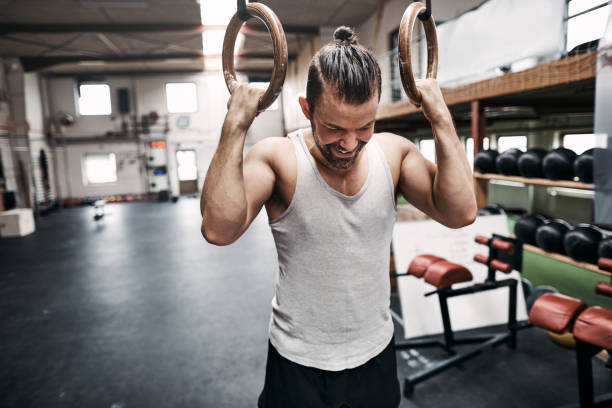 istock Fit young man smiling after exercising on rings 1043051442