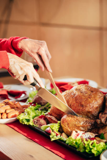 cropped image of woman slicing holiday delicious turkey at table