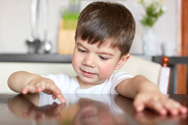 istock Small male preschooler has curious look at kitchen table, waits for brealfast, has appealing appearance, dressed in casual t shirt, has plump cheeks. Childhood and playing concept. I am ready to eat 1043058818