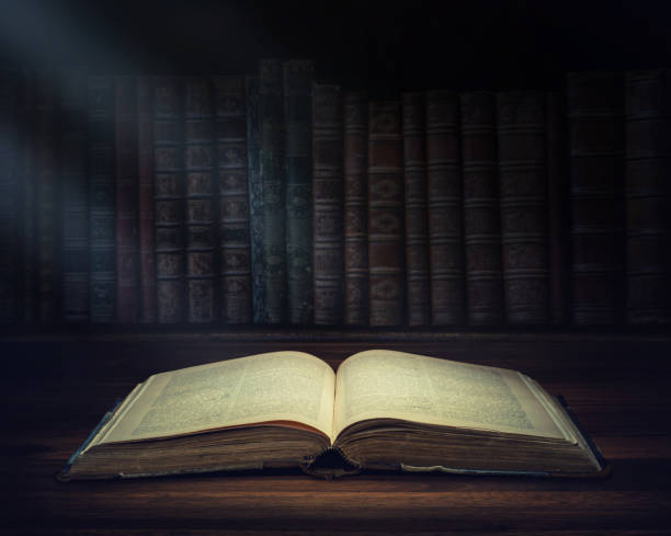 istock Open old book on a bookshelf background and the rays of light. Selective focus. Conceptual background on history, education, literature topics. 1043058992