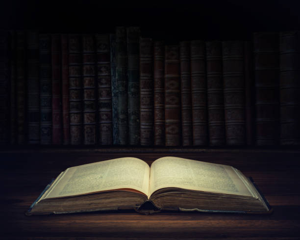 istock Open old book on a bookshelf background and the rays of light. Selective focus. Conceptual background on history, education, literature topics. 1043059062