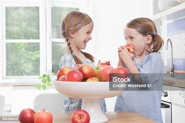 Alemanha Munique Raparigas A Comer Maçã Contra A Janela - Fotografias de stock e mais imagens de Comer