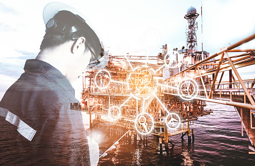 Double exposure of Engineer or Technician man with digital icon operated platform or plant by using tablet with offshore oil and gas platform background for industry business concept.