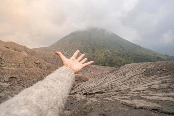 рука тянется к кратеру вулкана - bromo crater стоковые фото и изображения