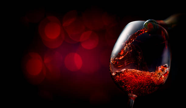 Wine on dark red Wine pouring into wineglass on dark red background maroon photos stock pictures, royalty-free photos & images