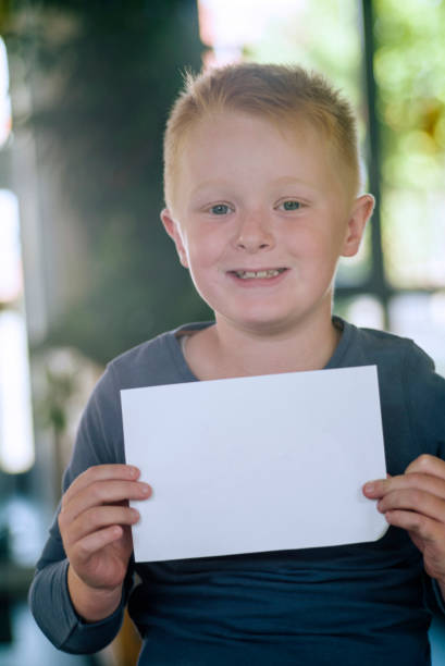istock Portrait: friendly smiling schoolboy,  holding a blank poster, looking at camera, 1043086322