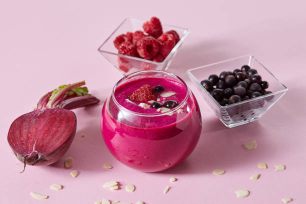 smoothies of red berries in a glass with half a beet, raspberries and black currants on a pink paper background. - vitality food food and drink berry fruit imagens e fotografias de stock