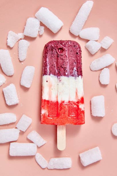 istock Multicolored berry ice cream on a stick with ice cubes on a pink background. Top view 1043088760