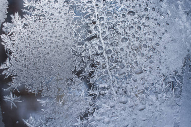 istock Close-up white frosty pattern formed from frozen water drops, on winter window. 1043118814
