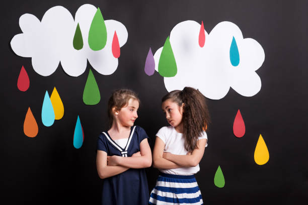 istock Small girls in studio, standing against black background with clouds and raindrops. 1043119578