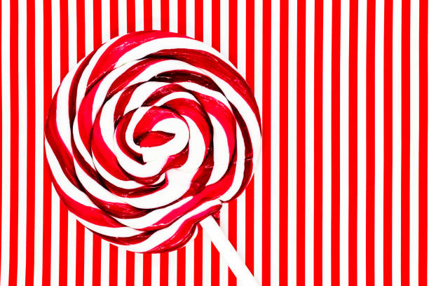 Round white and red lollipop with white stick on white and red striped background surface
