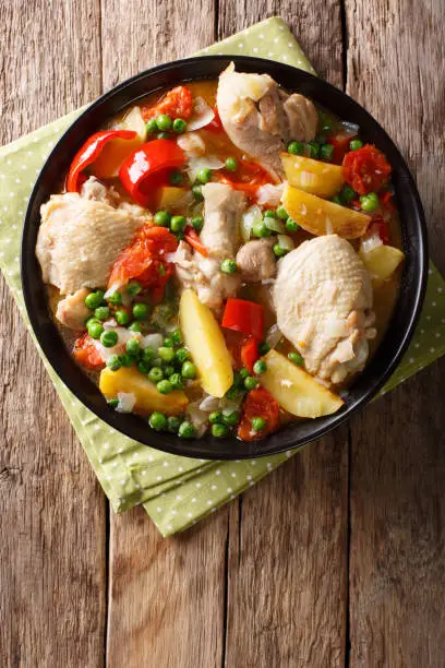 Photo of Chicken meat stewed with vegetables and spices close-up in a bowl. Vertical top view