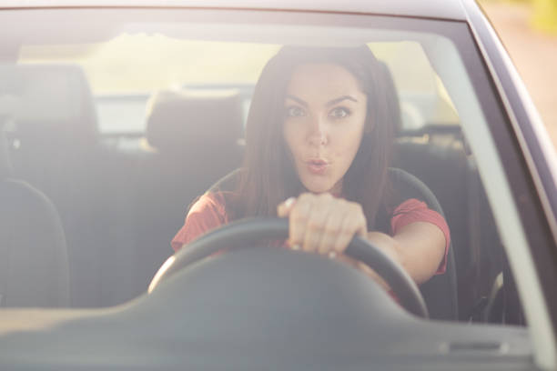 istock Stunned beautiful brunnette female drives car with shocked expression, sees something awful on road, keeps hand on wheel. View from windscreen. People, transport, danger, car accident concept 1043135172